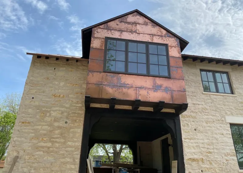 Copper metal panel facade on a stone building for Roof Repair in Marilla